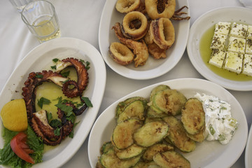 Greek food close up top view.  Taverna style food with octopus and squid seafood, feta cheese with oregano and olive oil and fried zucchini with tzatziki sauce.