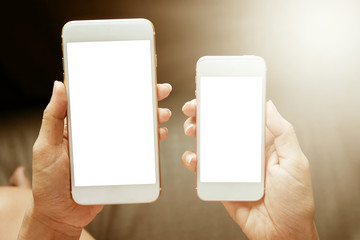 Women hands holding two smart phone with blank screen. close up shot.vintage lighting effect.
