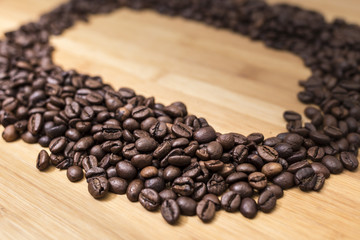 Dark coffee grains in a diagonal row on a wooden surface