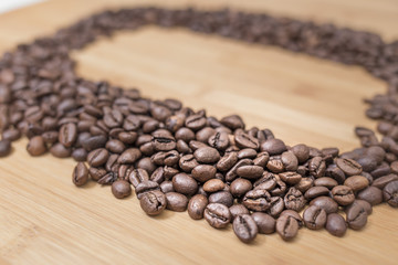 Dark coffee grains in a diagonal row on a wooden surface