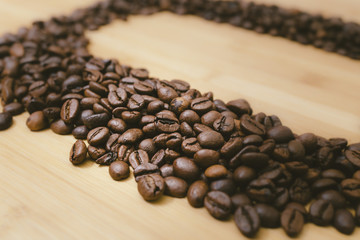 Dark coffee grains in a diagonal row on a wooden surface