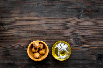 Oil as cosmetics. Walnut oil near walnut in nutshell on dark wooden background top view copy space