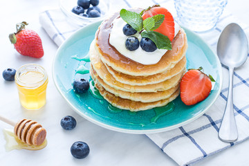 Stack of pancakes on the plate. Morning breakfast with berries on the table. Close up