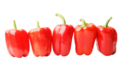 Five ripe red sweet peppers in the row isolated on white