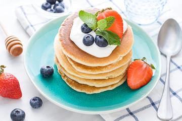 Stack of pancakes on the plate. Morning breakfast with berries on the table. Close up
