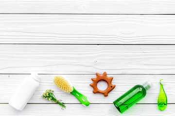 Children's means hygiene with chamomile. Bottles, spa salt, tooth brush and toy on white wooden background top view copy space