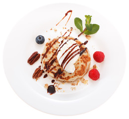 Serving pancakes with ice cream and fresh berries on the plate.Decorated with chocolate syrup. Isolated on white background.