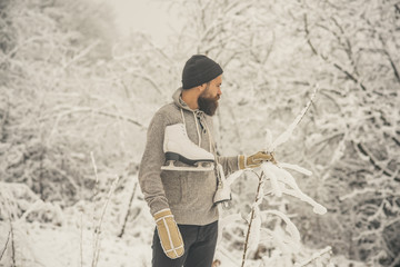bearded man hold skate in snowy winter forest, christmas