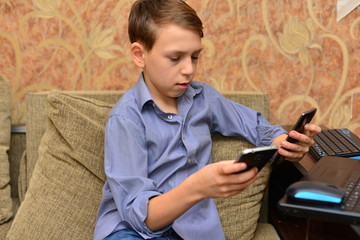 Fototapeta premium Angry man having problems on line with a laptop talking on the mobile phone with support service sitting on a couch in the living room at home