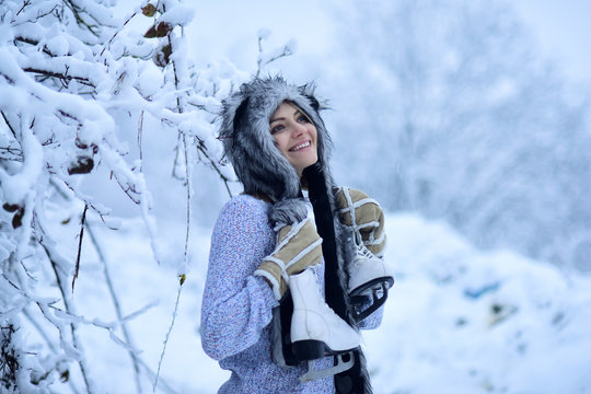 Happy girl smile with figure skates at trees in snow