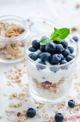 Healthy breakfast of homemade granola cereal with blueberries, nuts and fruit, honey with drizzlier background. Morning food, Diet, Detox, Vegetarian concept.