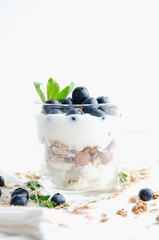 Healthy breakfast of homemade granola cereal with blueberries, nuts and fruit, honey with drizzlier background. Morning food, Diet, Detox, Vegetarian concept.