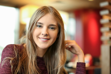 Obraz premium Portrait of beautiful smiling young woman in cafe