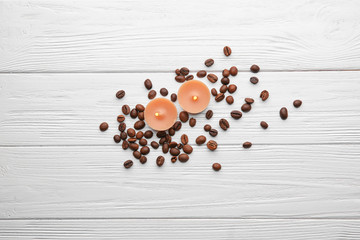Beautiful composition with coffee beans and burning candles on wooden background