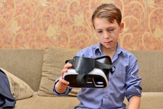 Happy teen boy wearing virtual reality goggles watching movies or playing video games. Cheerful smiling looking in VR glasses and making thumb up gesture. Child experiencing virtual reality.