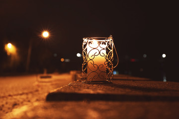 Fototapeta na wymiar Holder with burning candle at night, outdoors