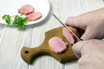 A man is cutting smoked meat