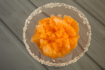 Frozen juice with mandarins in the wineglass on the grey  wooden background.View from above.