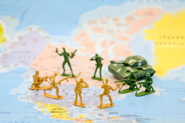 War and military concept. Group of miniature soldiers toy with tank on world map