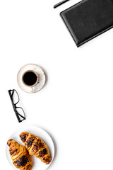 Light breakfast of businessman. Coffee and croissant near notebook and glasses on white background top view copy space
