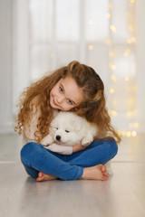 Little curly girl with a samoyed puppy