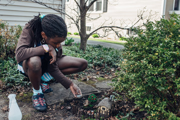 African American girl building a fairy house in a garden