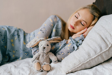 Young beautiful blonde teen sleeping on vintage wooden bed. Cute lovely girl resting on old french...