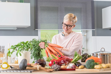 Junge Frau freut sich aufs Kochen, des frisch gekauften Gemüses