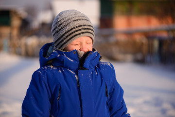 Child in winter clothes outside the city on the background of a snowy winter landscape.
