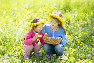 Small children outdoors collect Easter eggs in a basket
