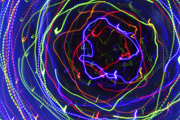 Movement in a spiral. Abstract dark background with bright multicolored neon lights