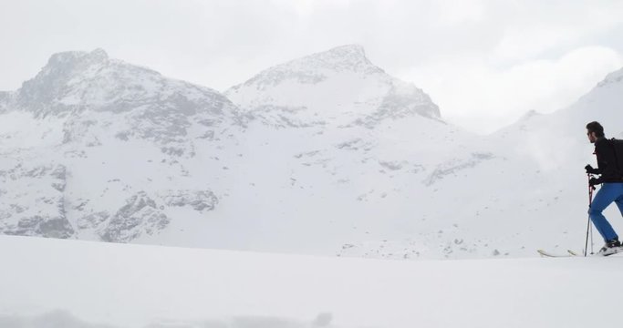 Man walking up ascending along snow ridge landscape with woman friend.Mountaineering ski activity. Skier people winter sport in alpine mountain outdoor.Side view.Slow motion 60p 4k video