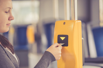 Young woman hand inserts the bus ticket into the validator, validating and ticking