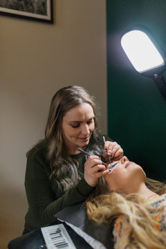 Young woman getting lash extension cosmetology laying down in small business studio