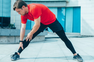 Sporty Young Man Stretching Legs Outdoors