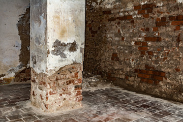 part of the room with destroyed brick walls, rectangular column with crumbling plaster at the base