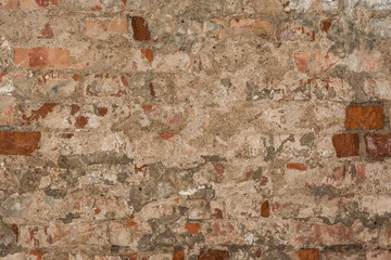 texture of an old wall of an ancient building with a ruined plaster layer and cracked red bricks
