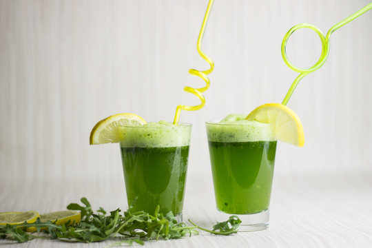 Fresh green juice in two glasses. Wild rocket, parsley and lemon.