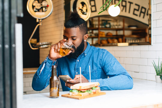 African american man using smartphone in a pastrami bar.