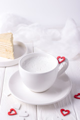 Obraz na płótnie Canvas Happy Valentine's day. White cup with milk, homemade honey cake and red hearts on a white background. Free space