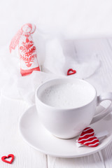 Happy Valentine's day. White cup with milk, homemade honey cake and red hearts on a white background. Free space