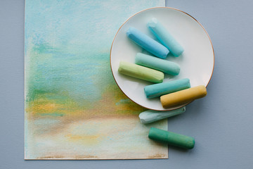 Soft pastel sticks on porcelain saucer on abstract pastel drawing