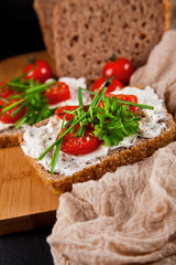 freshly prepared bread slices with cream cheese, tomatoes and chives