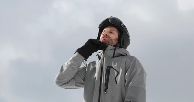 Man with helmet closing up soft shell jacket preparing for skiing.Mountaineering ski activity. Skier people winter sport in alpine mountain outdoor.Front view.Slow motion 60p 4k video