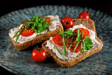 freshly prepared bread slices with cream cheese, tomatoes and chives
