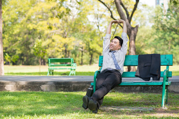 businessman sitting on horseback in green park with arms stretched to relieve fatigue from work