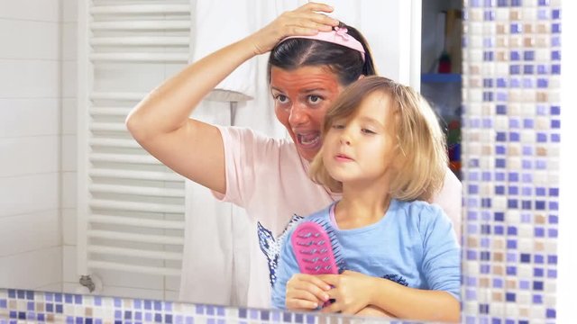 Happy mother and daughter dancing and singing in bathroom in front of mirror closeup