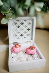 Fototapeta na wymiar White wooden box with two roses with wedding rings