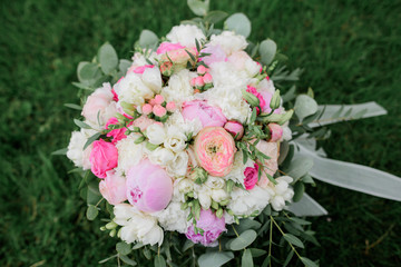 Rich wedding bouquet lies on green lawn