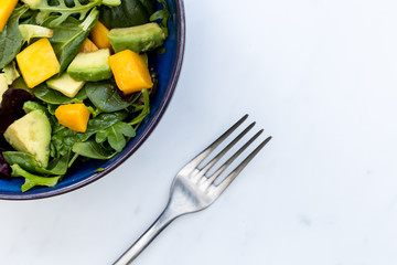 Healthy bowl of mango avocado salad and fork